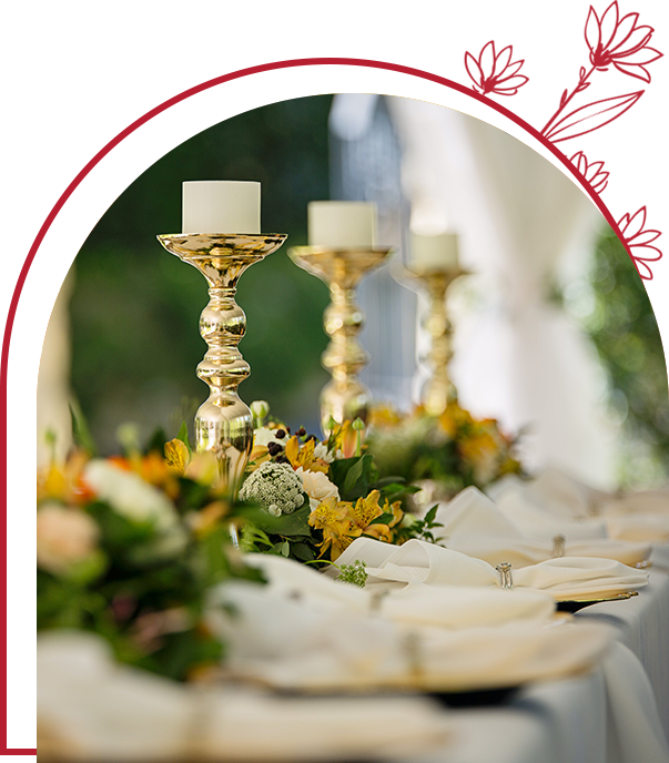 A table with three candles and flowers on it.