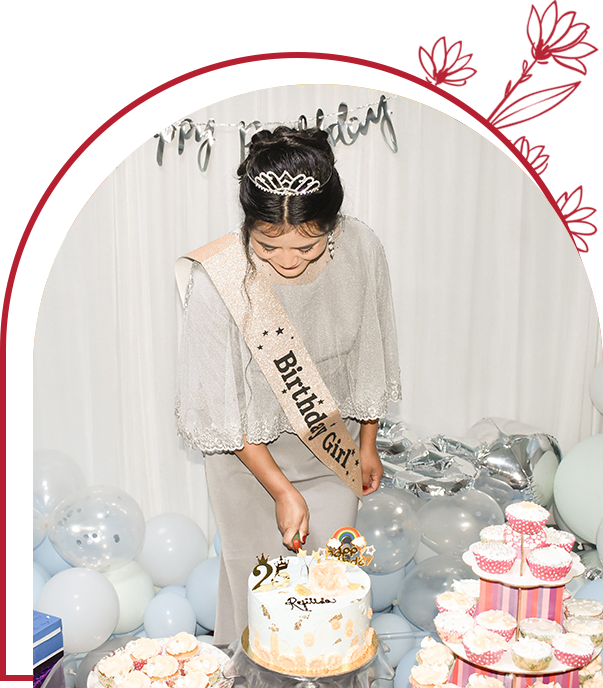 A woman in a tiara cutting into a cake.